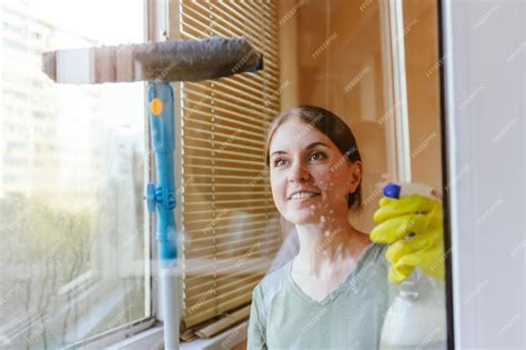 Femme de ménage souriante nettoyant une fenêtre