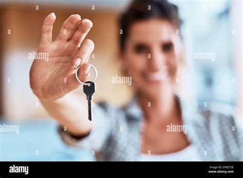 Femme souriante tenant une clé devant sa nouvelle maison